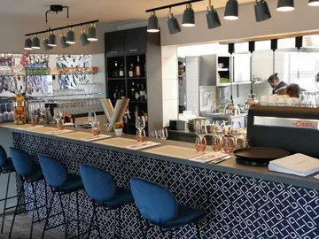 Moderne Bar mit Stühlen, Gläsern und offener Küche.