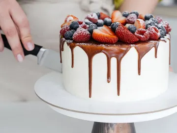 Kuchen wird mit einem Messer in Scheiben geschnitten.