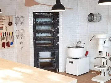 Kitchen with oven, appliances and cooking utensils on the wall.