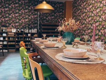 Langer Tisch mit bunten Stühlen, gedeckt für ein Essen.