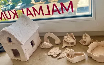 Keramikhäuschen und Figuren liegen auf einem Tisch.