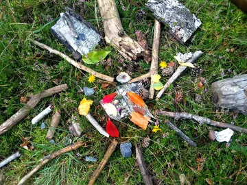 Äste und Blumen sind kunstvoll im Gras angeordnet.