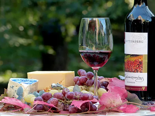 Red wine, cheese and grapes on an outdoor table.
