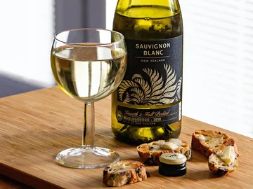 Weißwein steht neben einem Glas und knusprigem Brot.