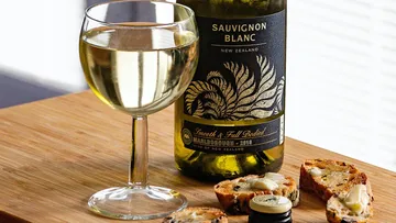 Weinglas mit Sauvignon Blanc, umgeben von Brotstücken.