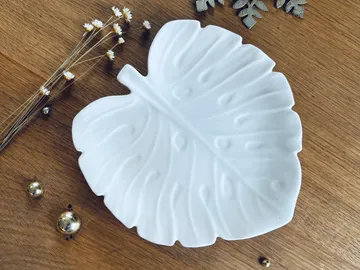 Weißes Blatt-Schüssel auf Holzoberfläche mit Dekoration.