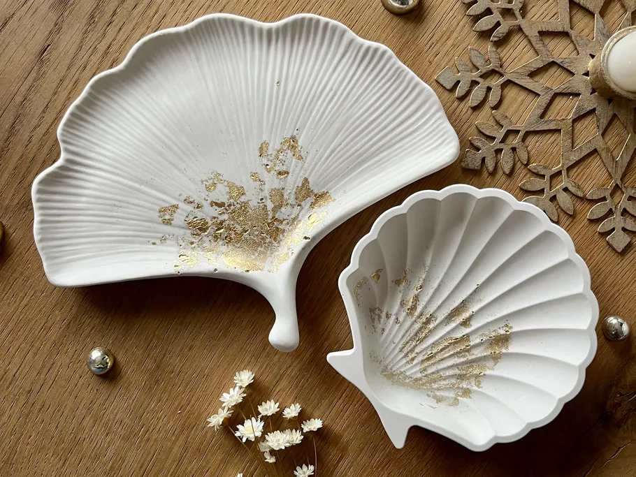 Weiße Muschelschalen liegen auf einem Holzuntergrund.