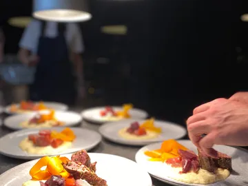 Küchenchef richtet kunstvoll Gerichte auf Teller an.