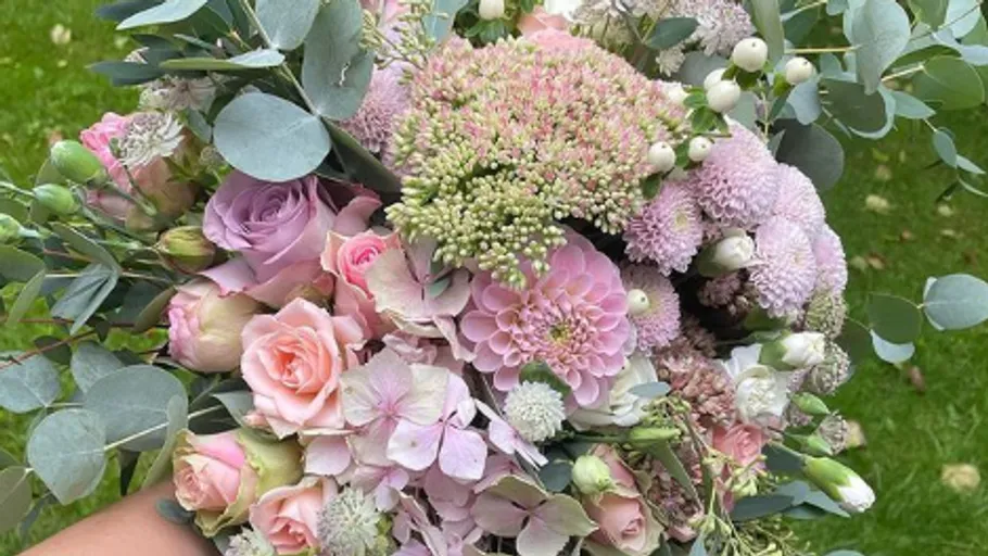 Colorful bouquets are held by one hand, green background.