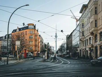 Straße mit Straßenbahnschienen, im Hintergrund Fernsehturm sichtbar.