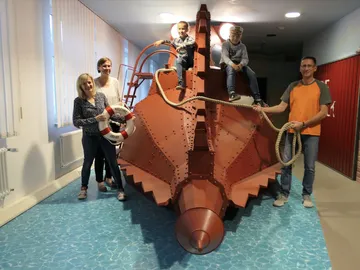 A red submarine replica with people on it in a room.