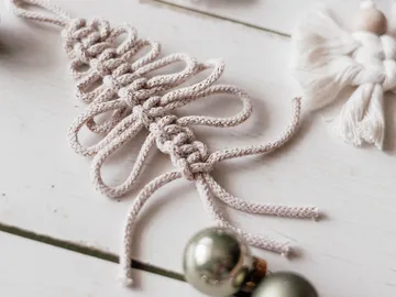 Knot made of fabric thread is lying on a white table.