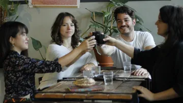 Four people toast with cups in a café.