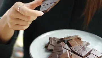 One hand is holding chocolate while the other is grasping.