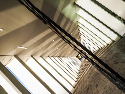 Lange, helle Flure mit Schatten und reflektierenden Oberflächen.