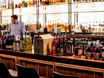 Bunte Flaschen stehen auf einer Bar, während jemand arbeitet.