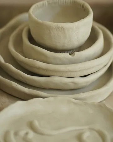 Tonkugeln und -schalen stapeln sich auf einem Tisch.