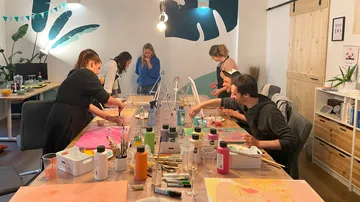 Group paints at tables in a creative, bright room.