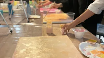 Paints are applied to canvases in a creative space.