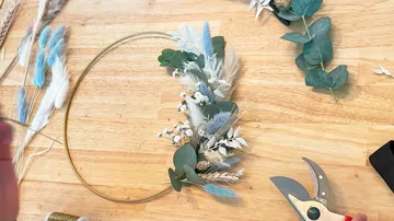 Blumenarrangement wird auf einem Tisch mit Werkzeugen gestaltet.