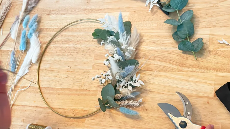 Blumenarrangement wird auf einem Tisch mit Werkzeugen gestaltet.