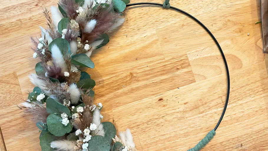 Circle ring decorated with dried flowers on a wooden background.
