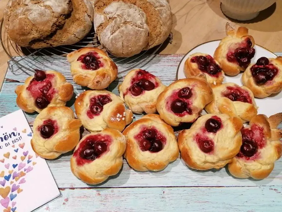Gebäck mit Kirschüberzug und Brot auf dem Tisch.