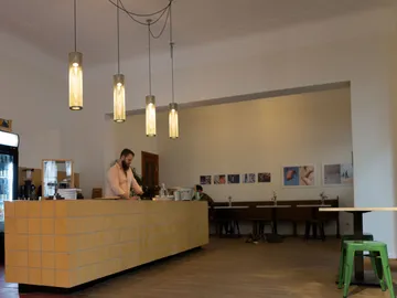 Ein Bartender arbeitet an der hellen Theke in einem Café.