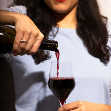 Eine Frau schenkt Rotwein in ein Glas ein.