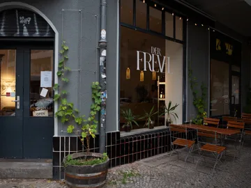 Restaurant with outdoor area, plants and an open door.