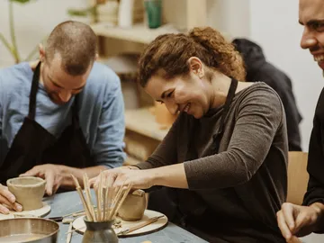 Three people make pottery in a creative studio.