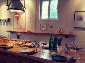 A set table with drinks and works of art in the background.