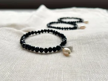 Black jewelry is placed on a bright, textured background.