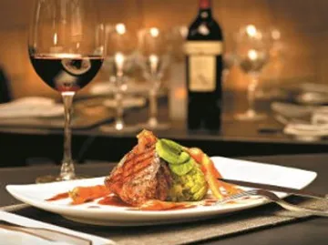 Gericht auf Teller, Wein nebenbei, elegantes Restaurant.