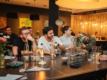 Gruppe von Personen lacht und kommuniziert in einem Restaurant.