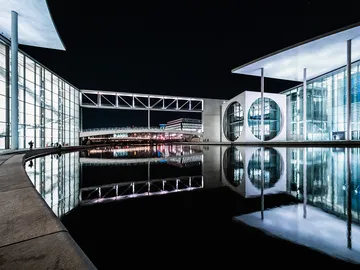 Modern building reflects in water at night.