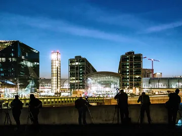Photographers observe a modern urban landscape at night.