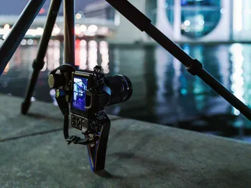 Camera stands on a tripod while taking pictures at night.