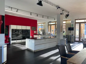Moderne Küche mit weißen Möbeln und roter Wand.