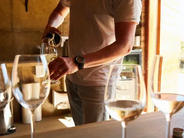 A man pours wine into glasses at the table.