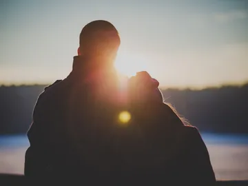 Couple hugging at the water before sunset.
