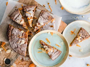 Pieces of cake lie on a board surrounded by plates.