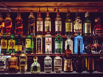 Shelf with many different liquor bottles in a row.