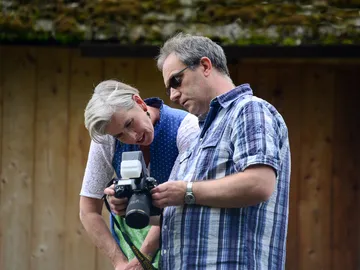 Two people are looking at a camera outdoors together.