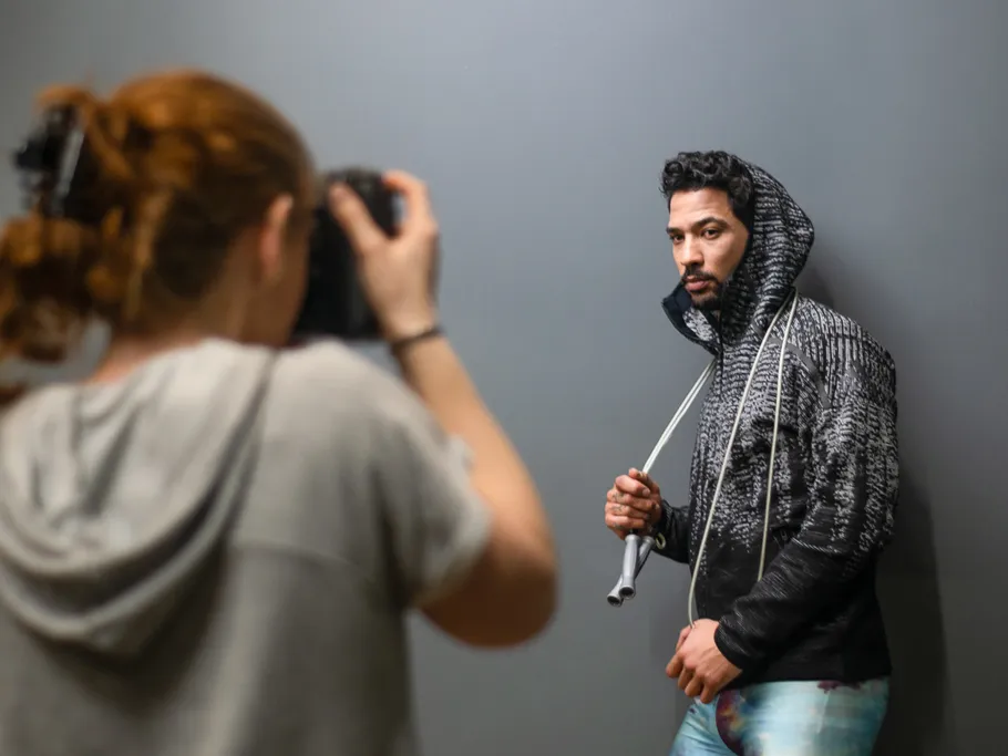 Mann posiert mit Kamera, während eine Person fotografiert.