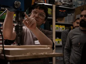 A man operates a drill in a workshop.