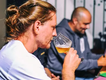 Mann trinkt Bier in geselliger Runde mit Freunden.