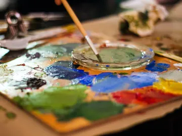 Palette with paints and brushes, when painting on table.