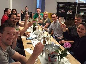 Group meeting, guests toast with glasses in bright surroundings.