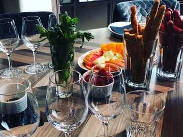 Glasses are placed on a table with fruit and snacks.